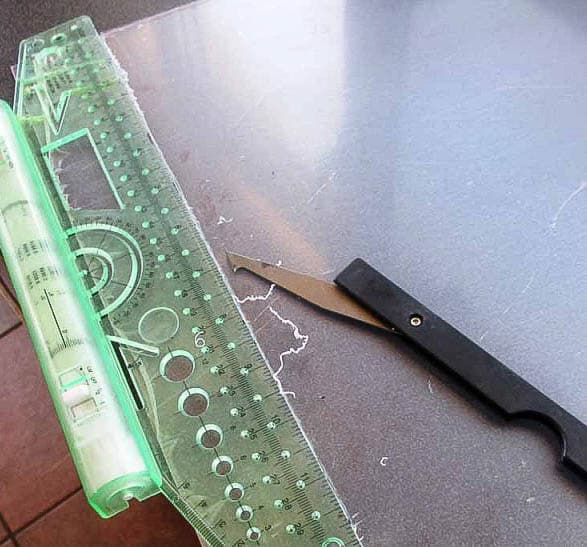 Closeup of a ruler on a plastic sheet with a special cutter.