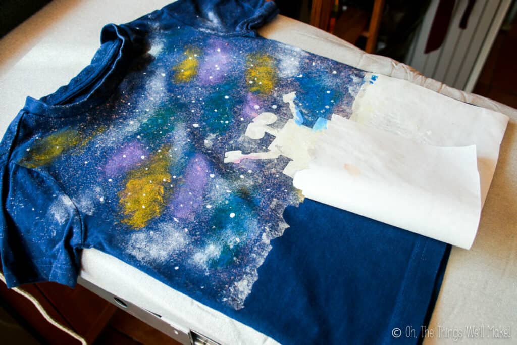 Removing the freezer paper stencil of Wall-E's silhouette to reveal the dark navy unpainted t-shirt below.