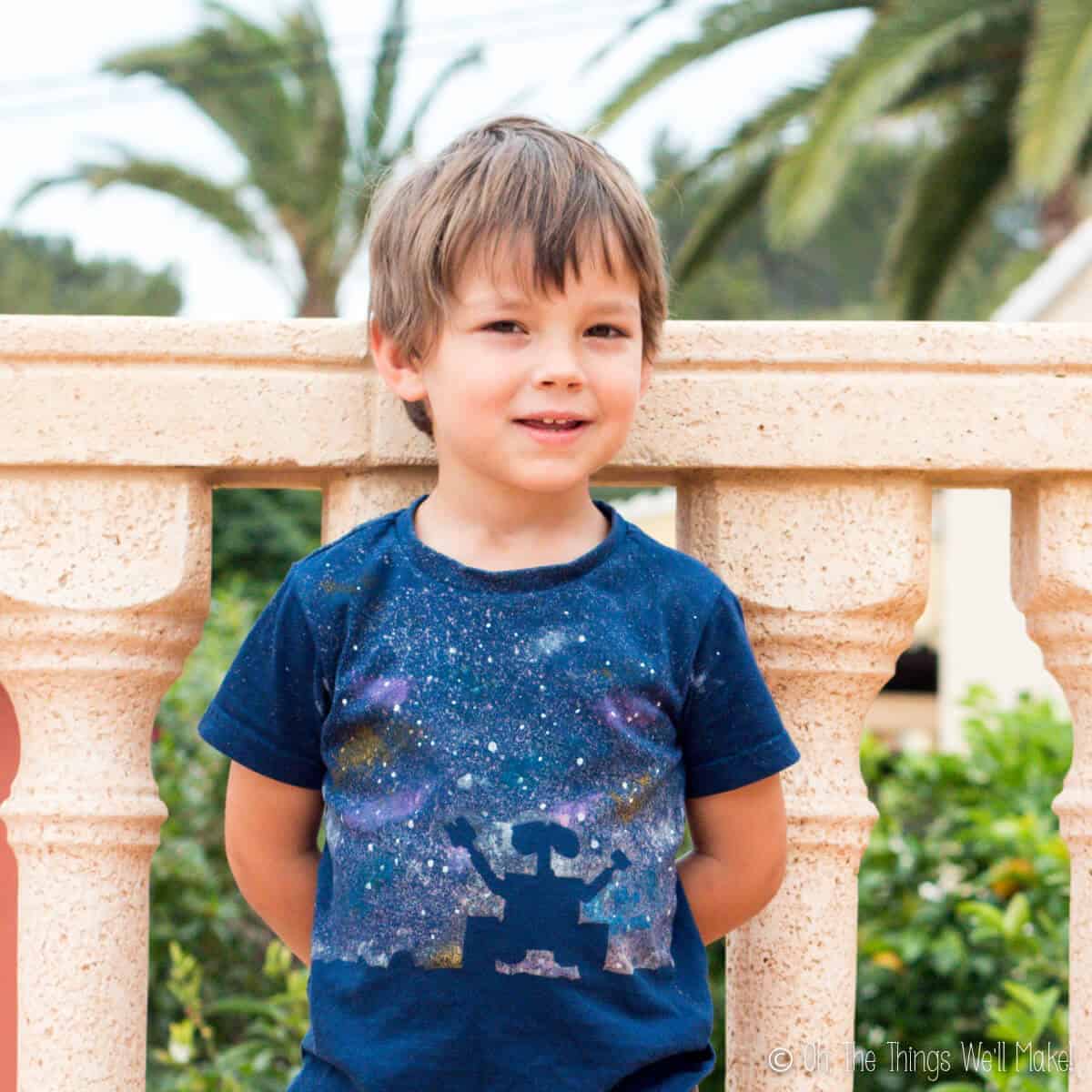 Boy wearing a handmade navy blue t-shirt with a silhouette of Wall-E and a starry galaxy background.