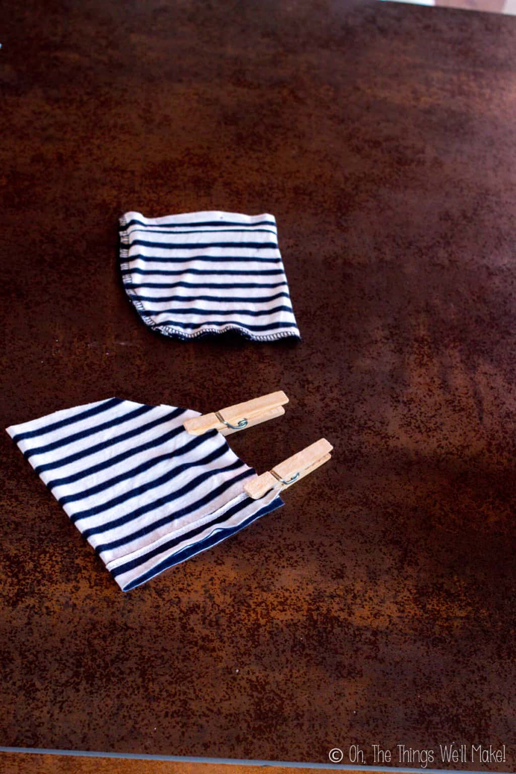 The sleeves of a striped shirt with the sides pinned with wooden clothespin, ready for sewing into a pouch.