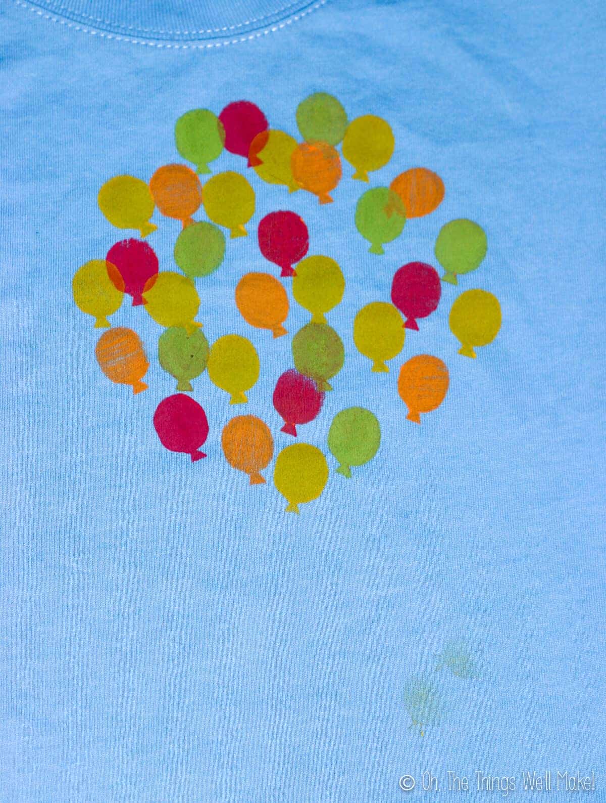 Top view of blue shirt with more balloons of different colors stamped on it.