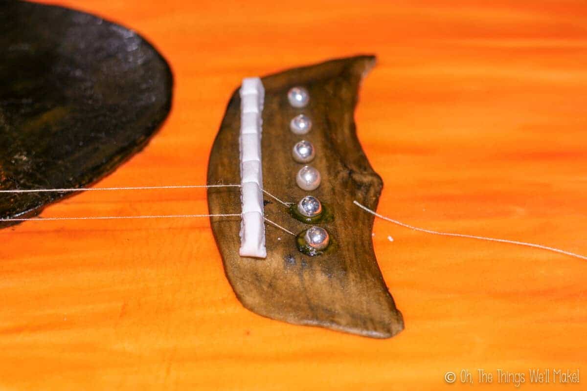 Close up of fondant bridge on the guitar cake. The chords are made of thread and fastened with silver ball candies.
