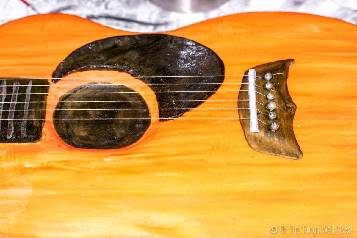 Close up of handmade fondant frets and strings over the sound hole of a guitar cake