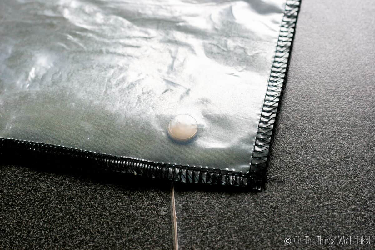 A closeup of a corner of a snack wrap showing a plastic button under a layer of transparent plastic.