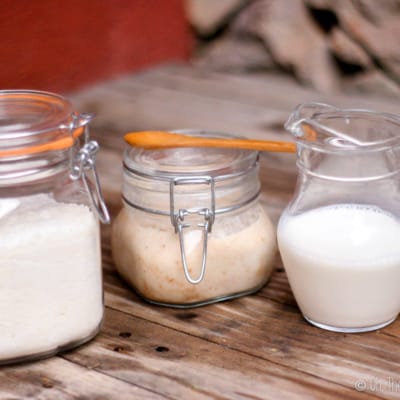 homemade coconut milk in a glass pitcher next to coconut flour and coconut butter in glass jars