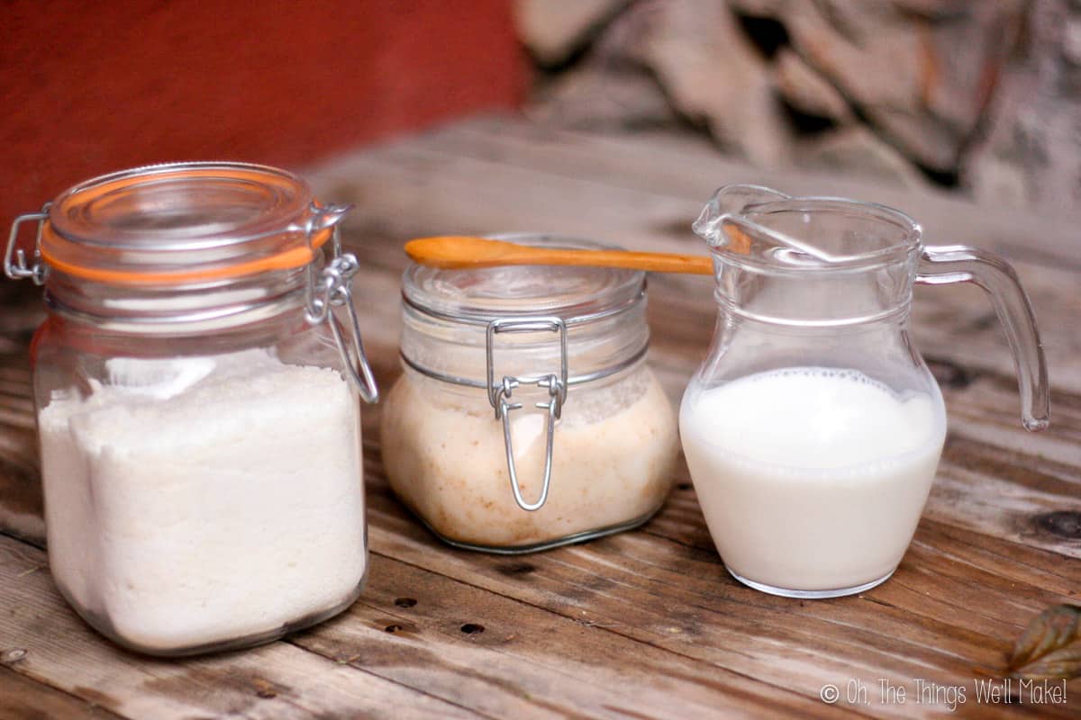 homemade coconut milk in a glass pitcher next to coconut flour and coconut butter in glass jars