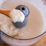 homemade coconut butter on a spoon over the food processor