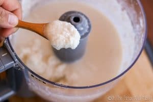 homemade coconut butter on a spoon over the food processor