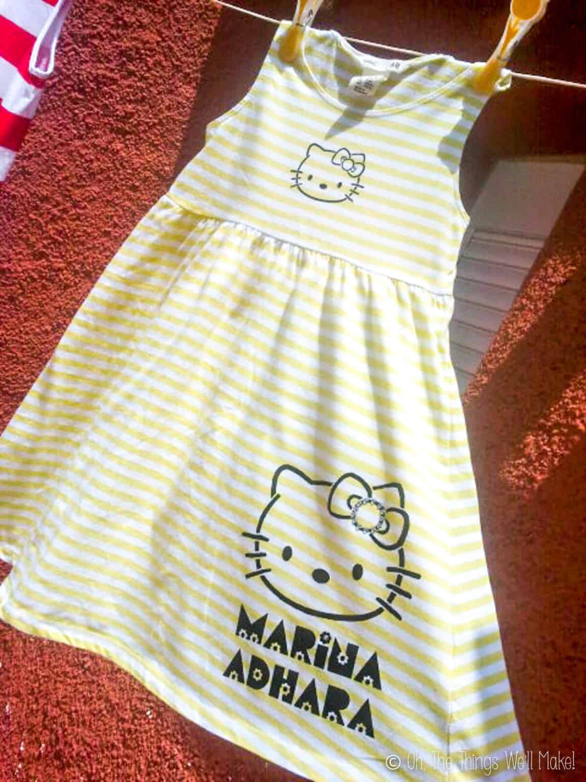 Close up of a yellow and white striped  sleeveless dress painted with Hello Kitty.