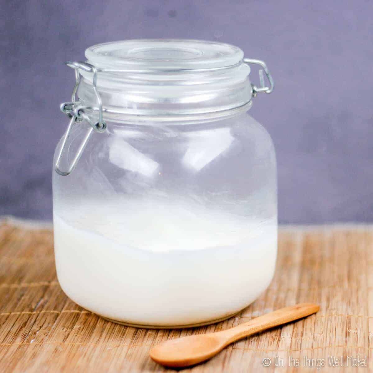 Large jar with home rendered lard and a wooden spoon in front of it.