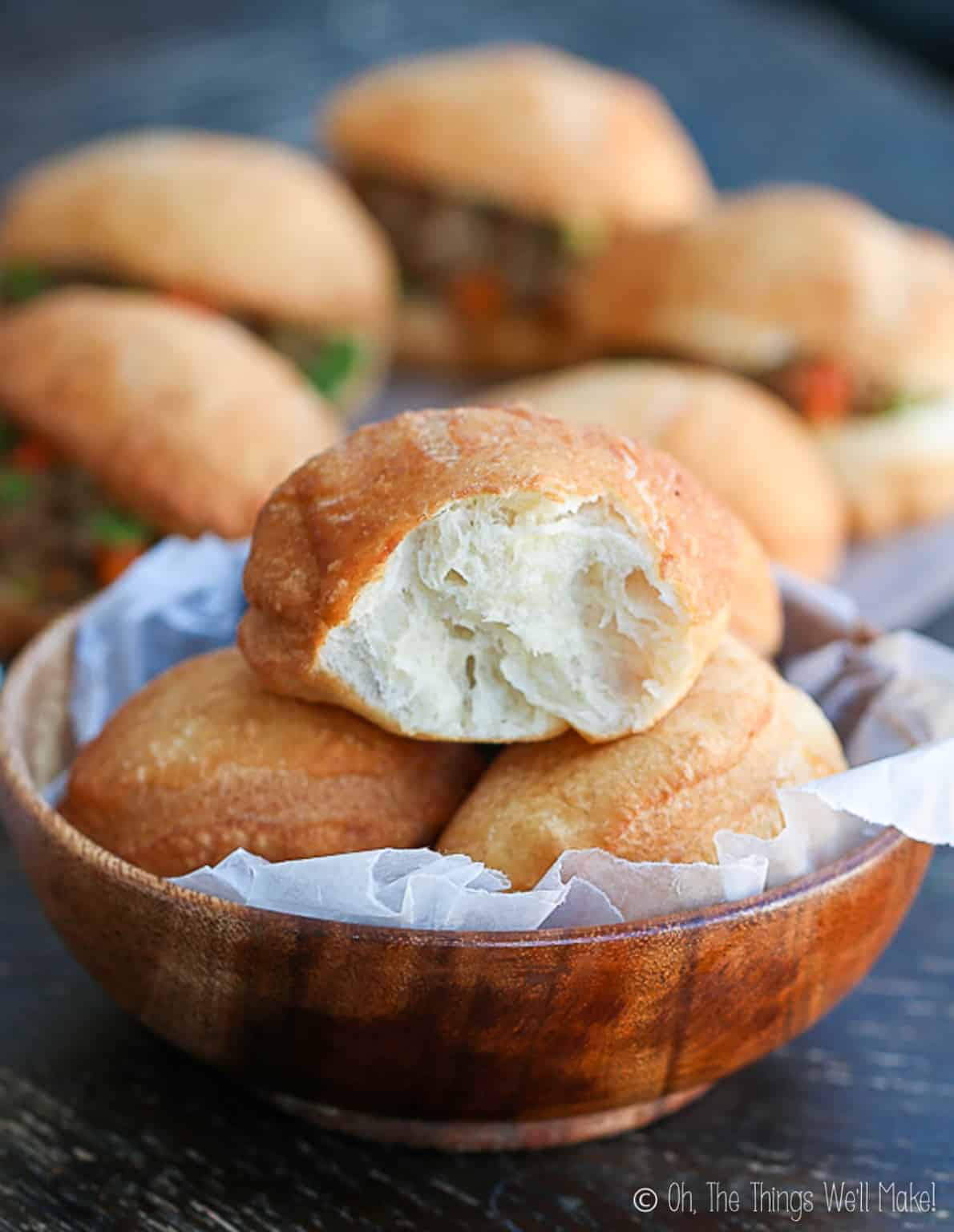 A bowl of vetkoek, South African fat cakes, in front of a plate of vetkoek with meat filling