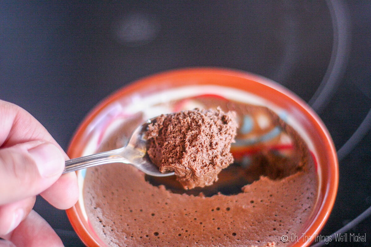 Close-up of homemade chocolate mousse being spooned up from a bowl showing off the fluffy texture.