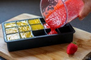Pouring mango and strawberry purees into an ice cube tray