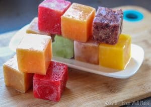 a rainbow of different colored frozen fruit ice cubes