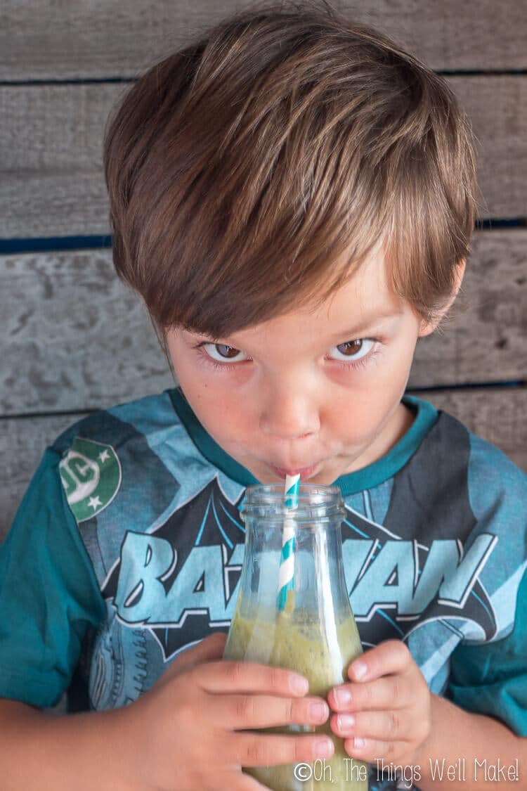 A young boy drinking a smoothie through a straw