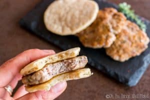 Closeup of a homemade sausage patty between two paleo pitas being eaten like a sausage biscuit