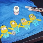 Closeup of painted minions across the bottom of a blue t-shirt.