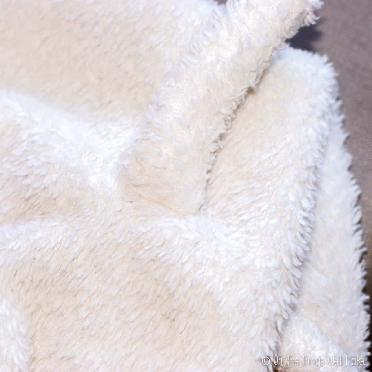 Close up of a tail sewn on a white blanket.