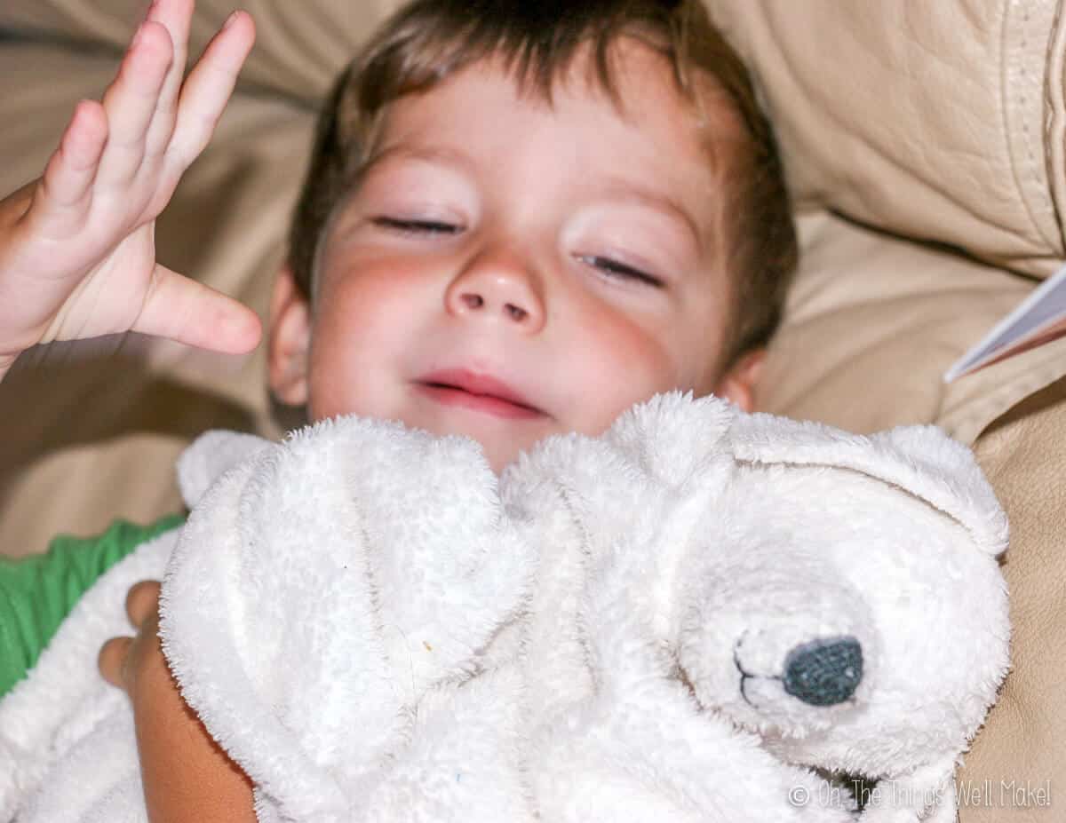 A young boy holding a white fluffy blanket with a puppy head on it. 