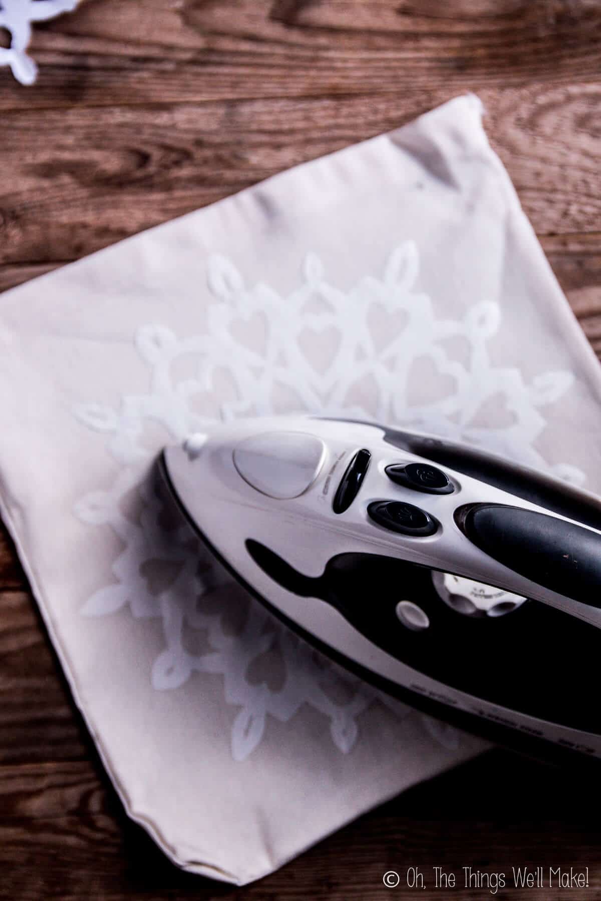 Ironing a freezer paper snowflake onto a fabric bag.