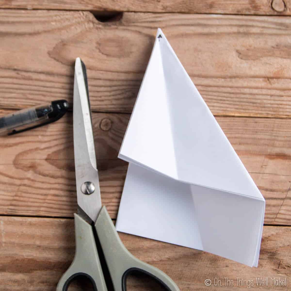 A piece of paper that has been folded several times and then marked in the center point with an arrow.
