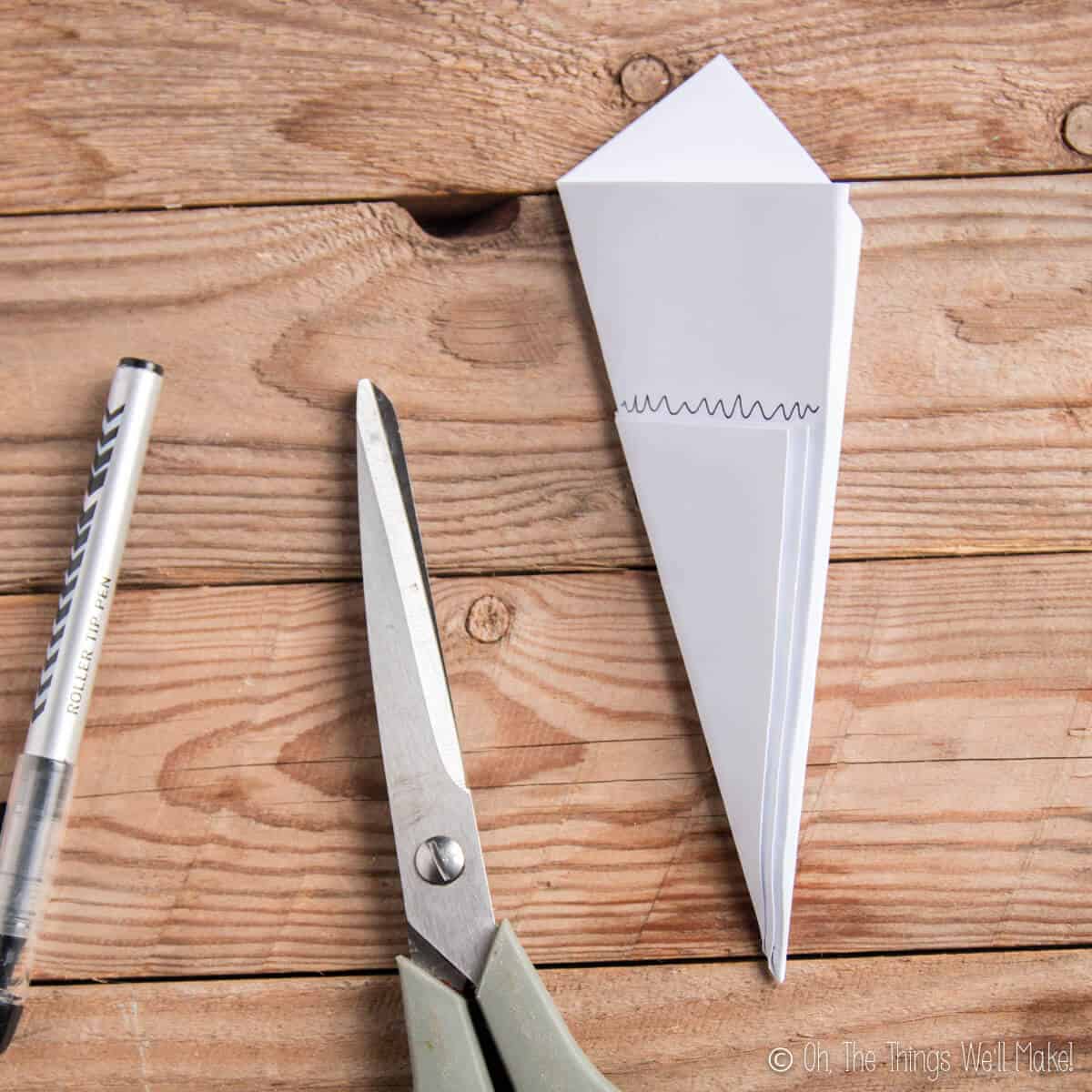 Paper that has been folded for cutting out paper snowflakes with a line drawn where the paper will be cut.