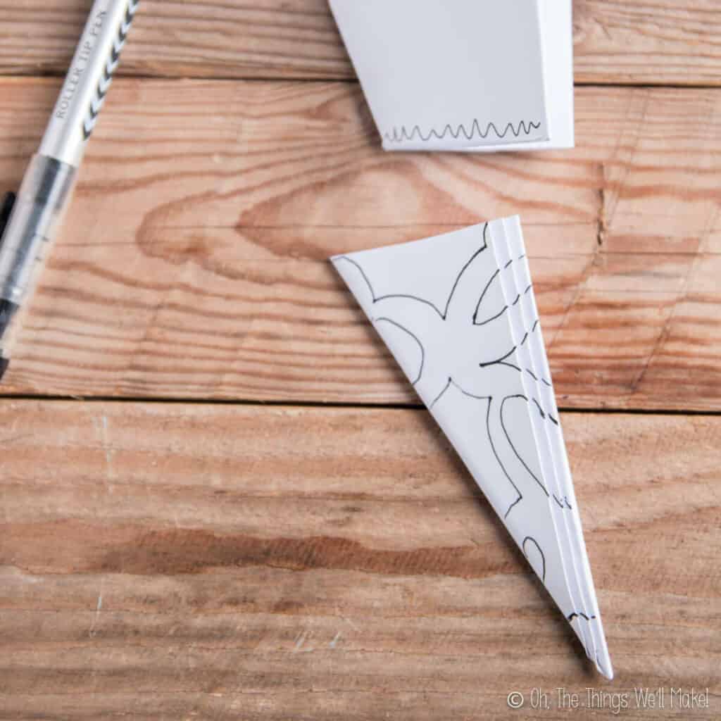 A piece of paper that has been cut for a paper snowflake. Lines have been drawn where the cuts will go.