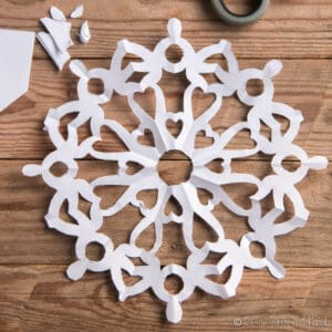 A paper snowflake made in the shape of a mandala with hearts and circles.