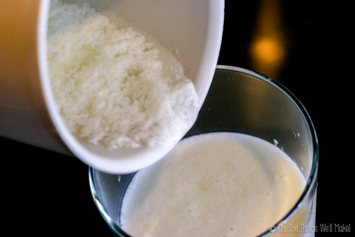 Close up of the kefir texture in a white container being poured into a glass of milk.