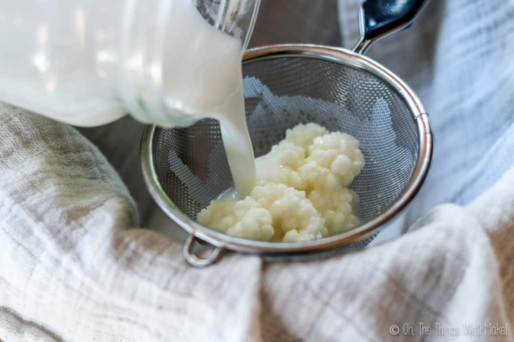 straining out the kefir grains with a stainless steel strainer