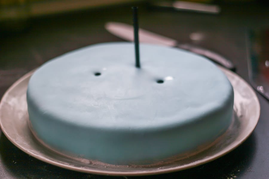 Poking a straw into a fondant cake.