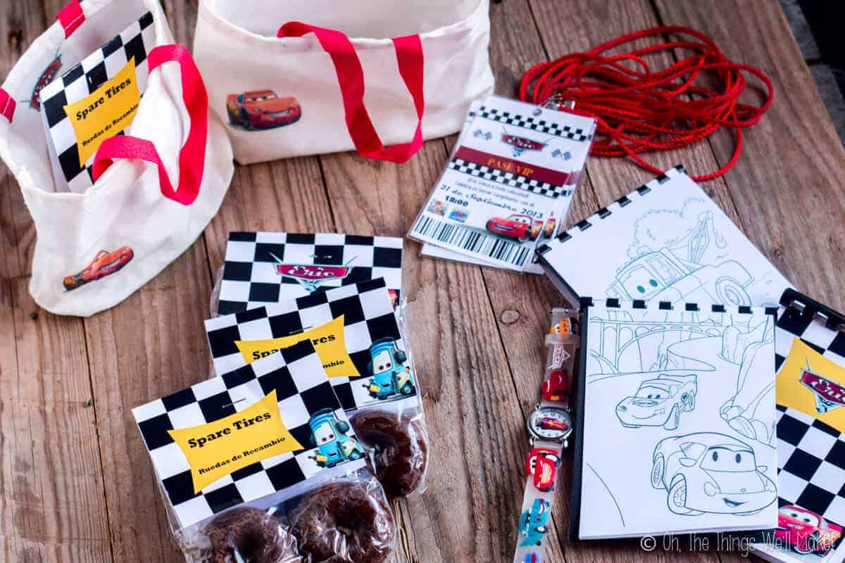 Cars party favors- including small cloth tote bags filled with donut "spare tires", Cars themed watches, and small coloring books with a Cars theme.