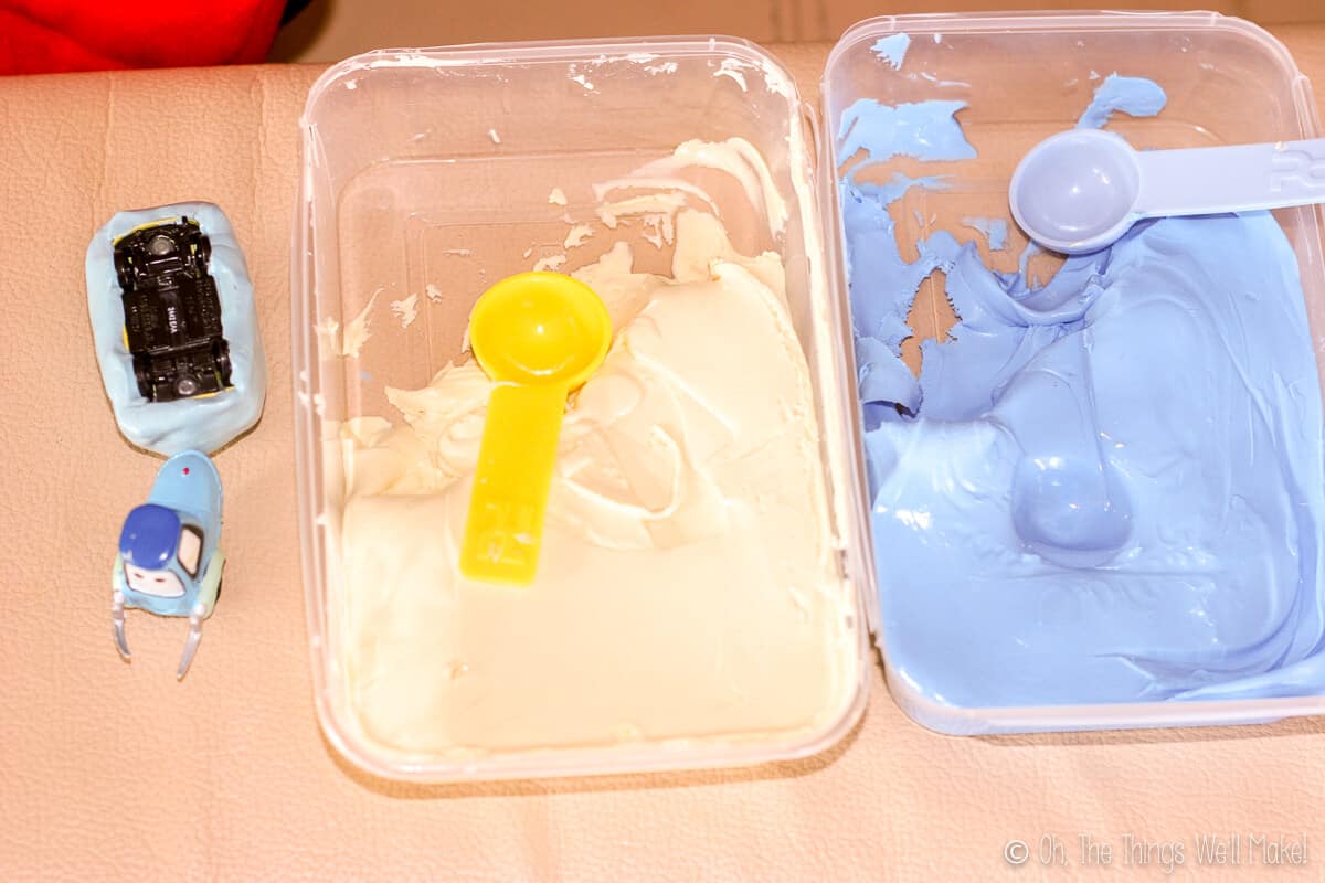 A small toy of Guido from Cars next to two containers filled with component silicone, ready to make molds for fondant.