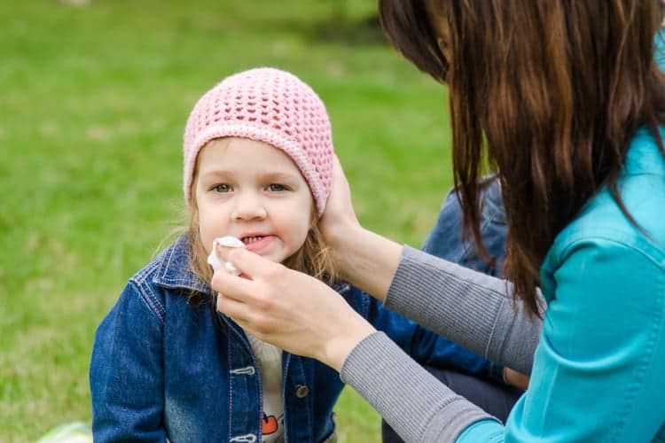 mother wipes child's face with baby wipe