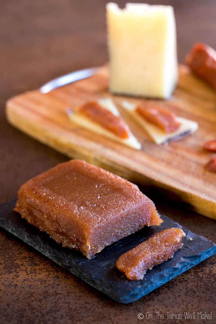 membrillo on a platter in front of a cutting board with cheese