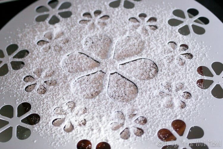 using a template to decorate the top of the St. James cake with powdered sugar