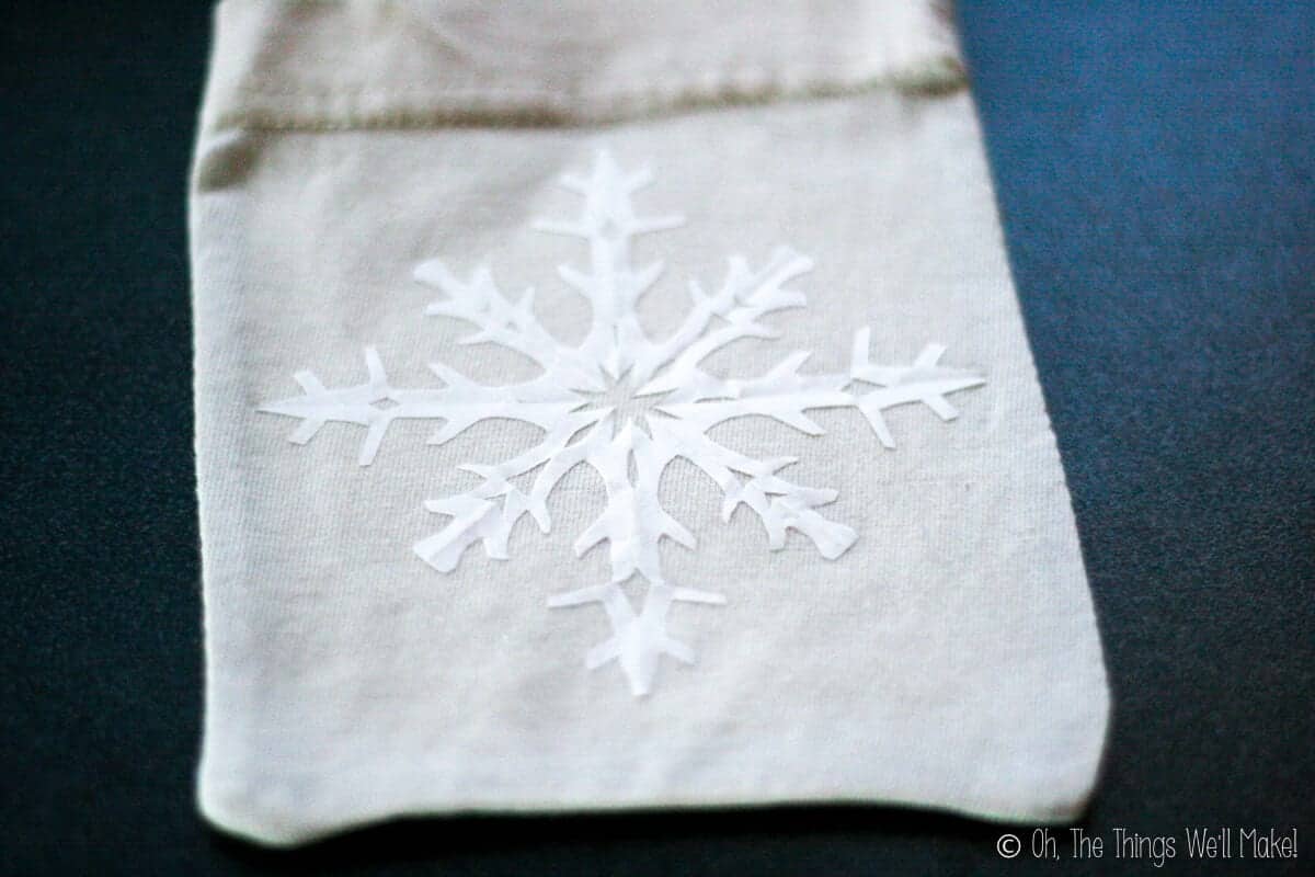 A cloth pouch with a freezer paper snowflake ironed on the front.