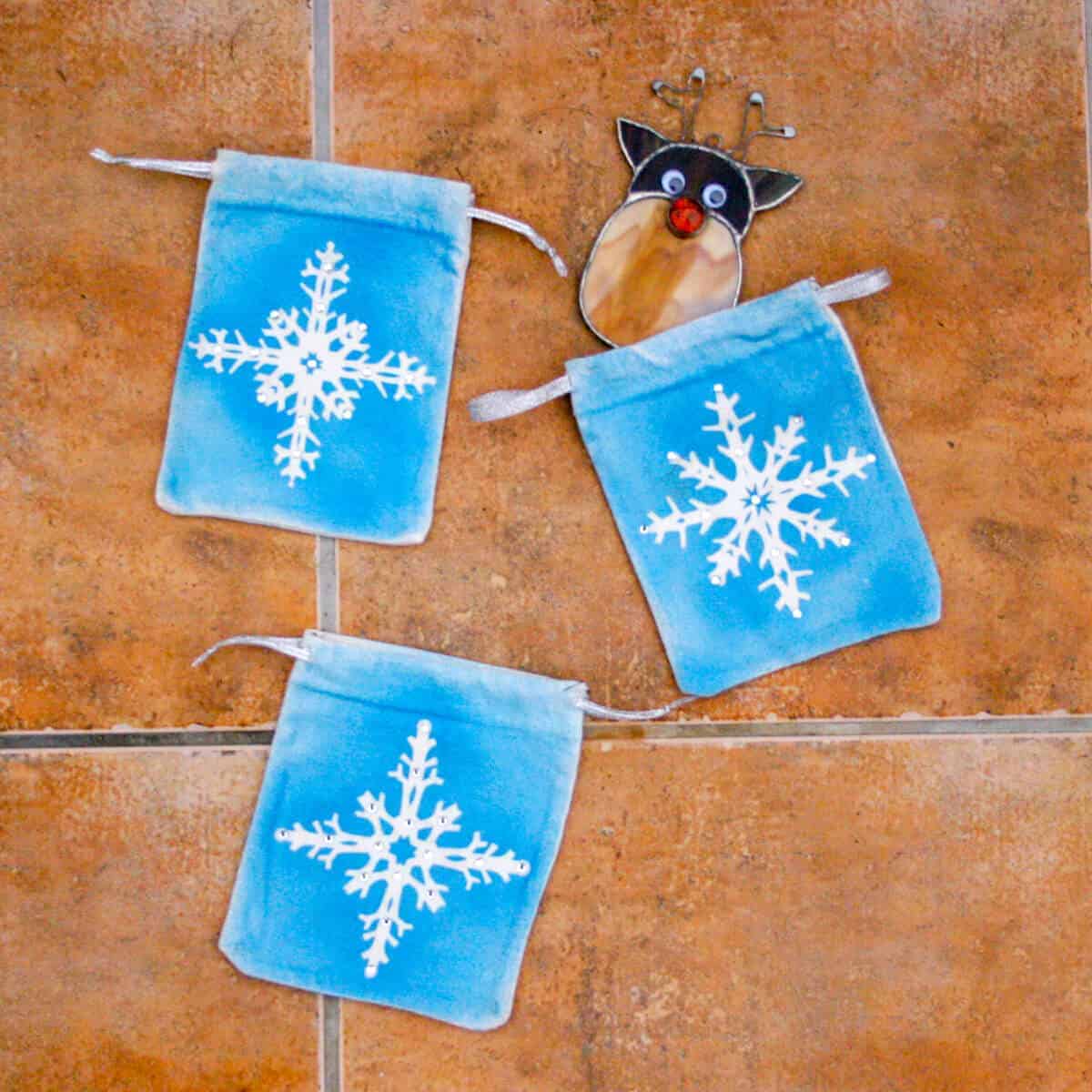 3 snowflake pouches with a homemade stained glass reindeer ornament