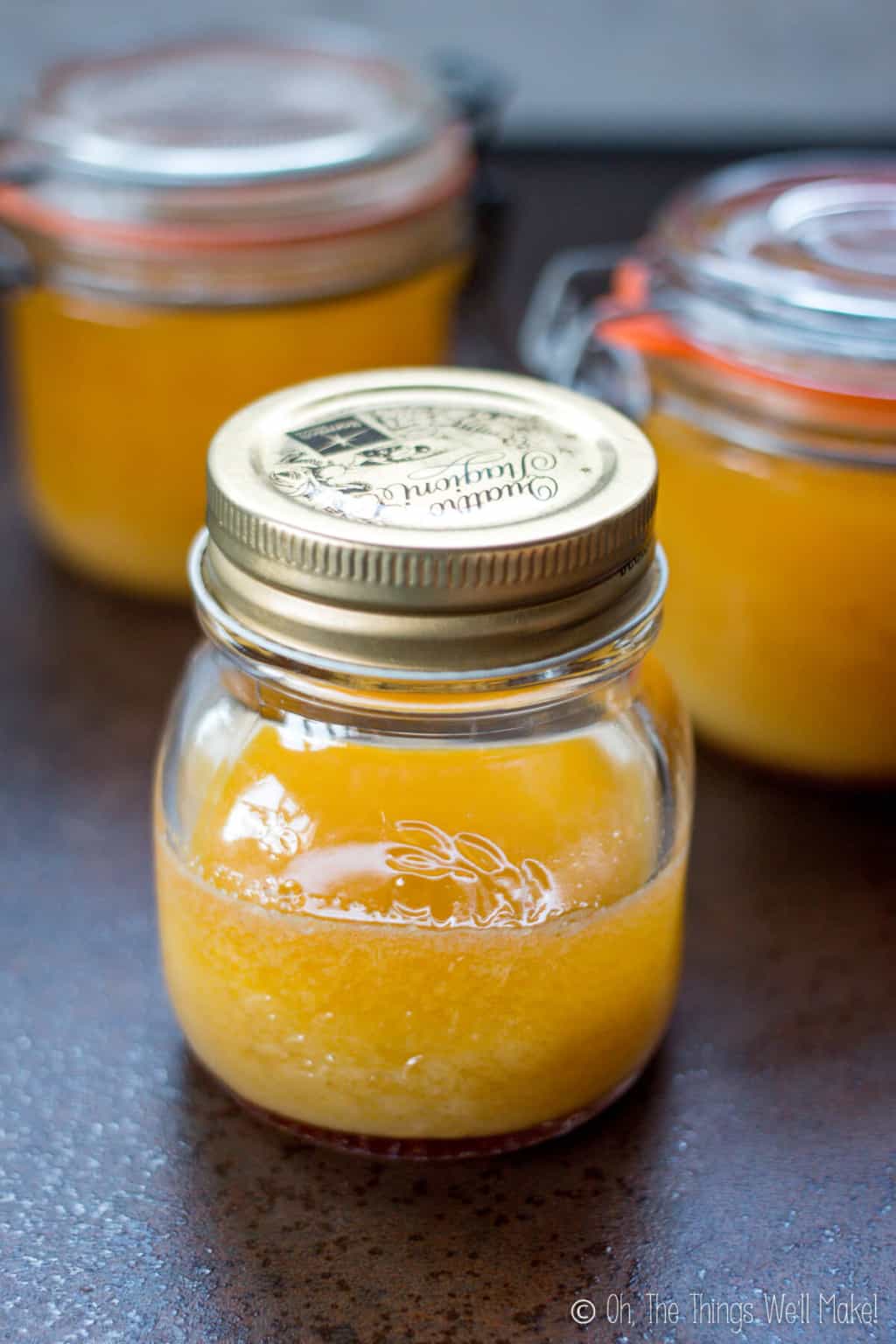 Close up of three glass jars of homemade ghee in their liquid state.