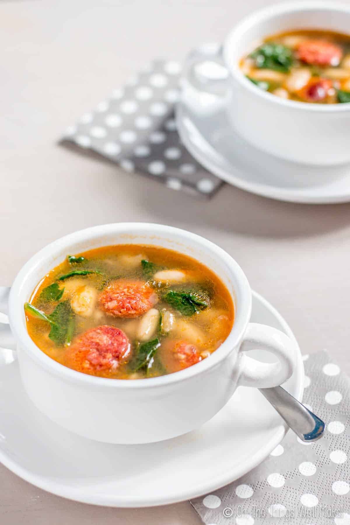 Two bowls of white bean and chorizo soup with spinach