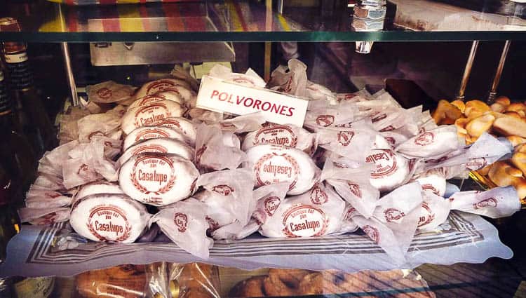 A bunch of wrapped polvorones cookies on a tray in a bakery window.