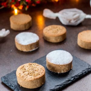 An assortment of homemade mantecados and polvorones on a black slate plate.