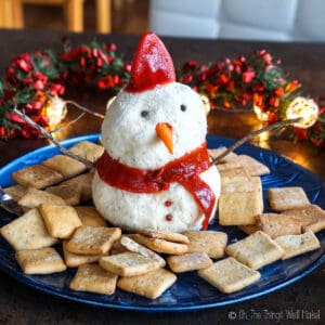 A snowman made out of cream cheese surrounded by square crackers.