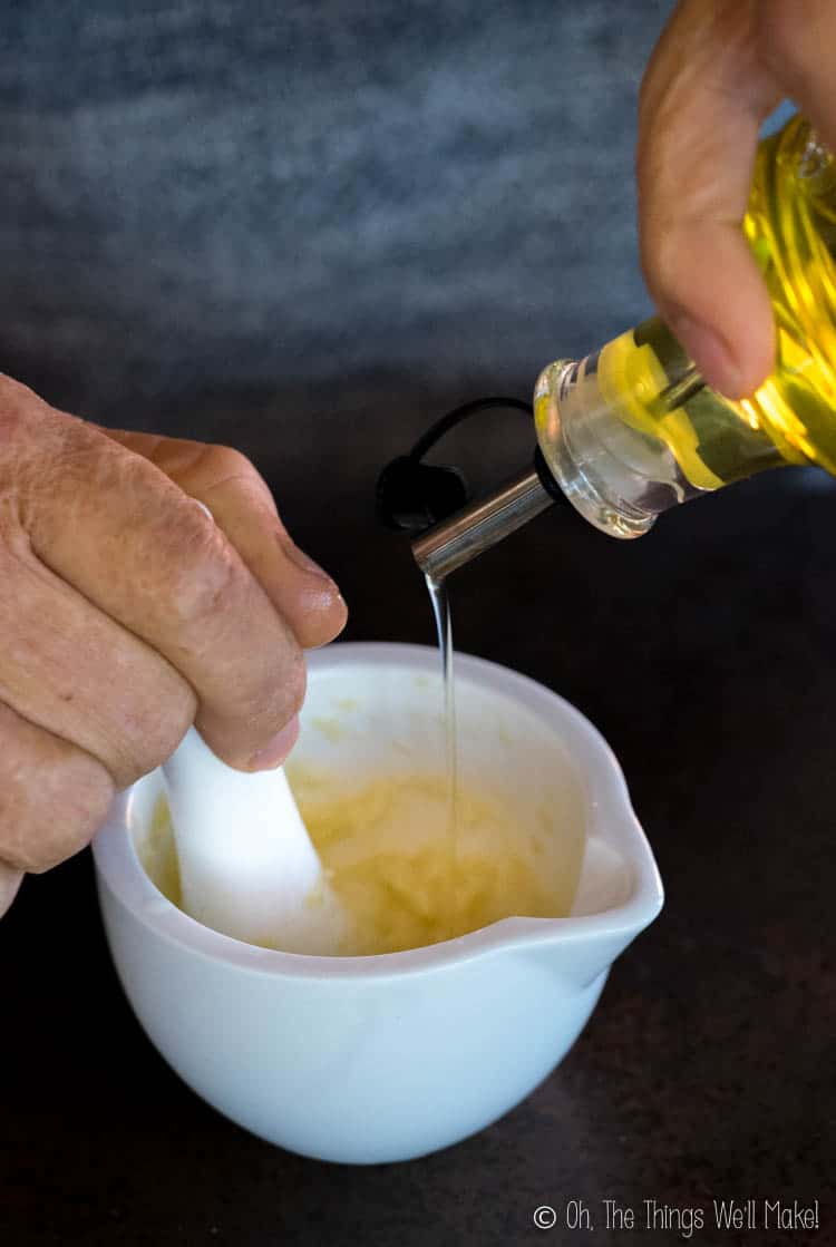 Traditional aioli being made with only garlic and olive oil with a mortar and pestle.