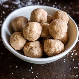 Closeup of coconut date balls in a white bowl.