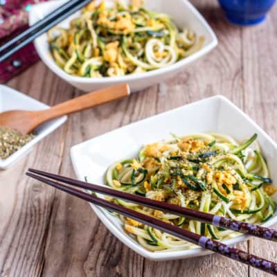Two bowls full of homemade zucchini noodles with chopsticks on the top side of the bowls.