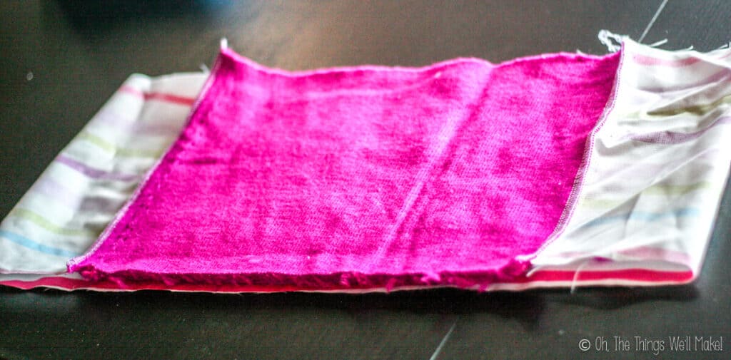 A tube of fabric made by sewing the pink fabric to the striped lining fabric, showing the wrong sides of the fabric.