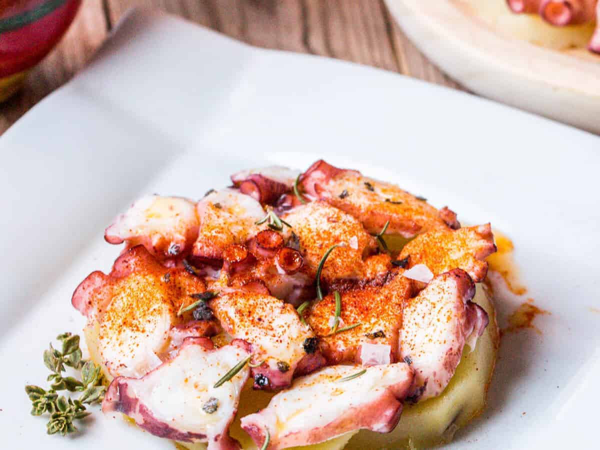 Close up of a plate of pulpo a la gallega, galician style octopus garnished with paprika.