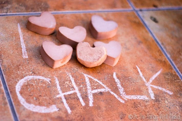 Picture with "I" written on the ground followed by several pieces of heart-shaped chalk, followed by "chalk."