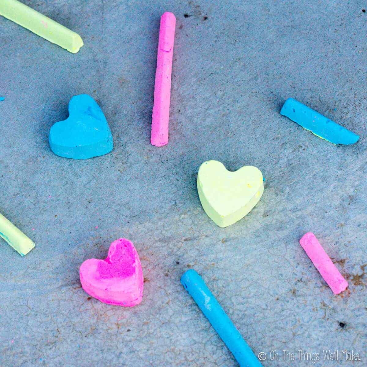 Overhead view of several pieces of homemade sidewalk chalk in three bright colors: pink, blue, and yellow.